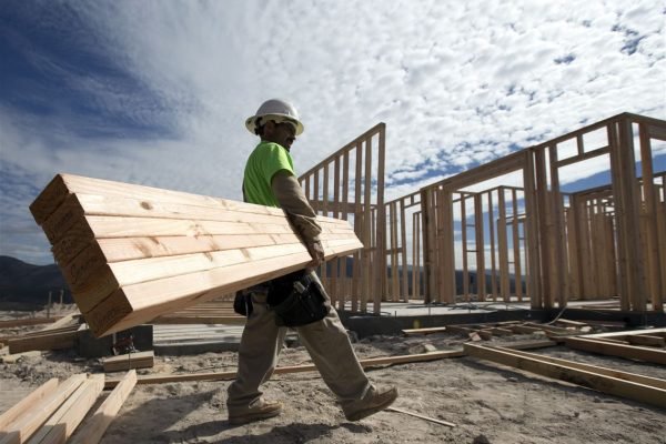 Construction-worker-Miguel-Fonseca-carries-lumber-as-he